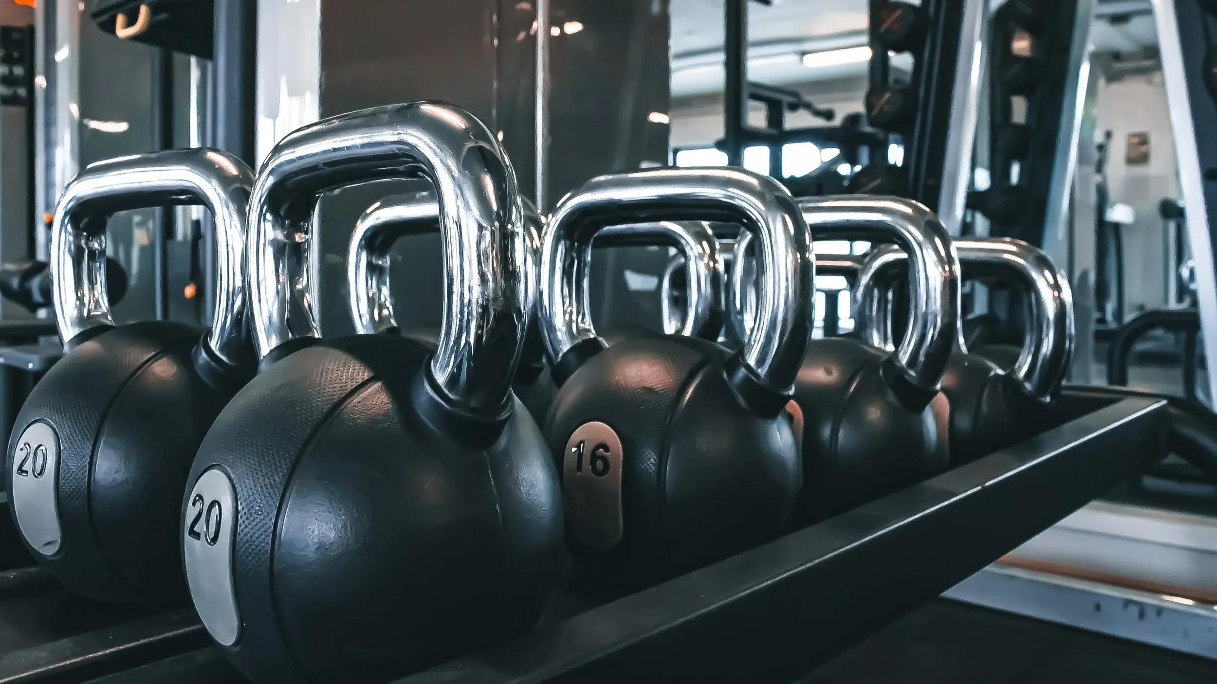 A rack of kettlebells and medicine balls on the gym floor