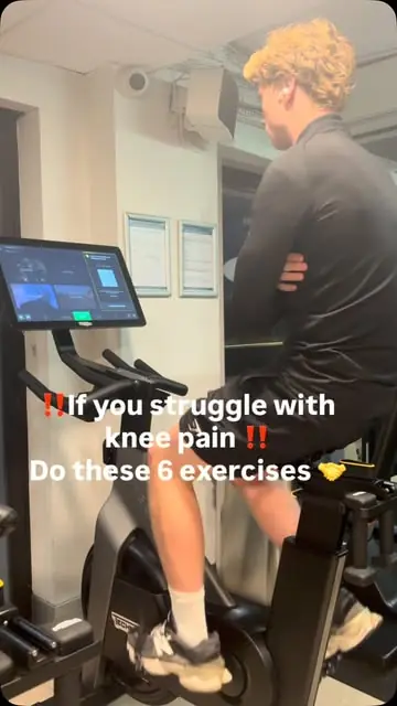 A member being coached through a knee exercise on the gym floor
