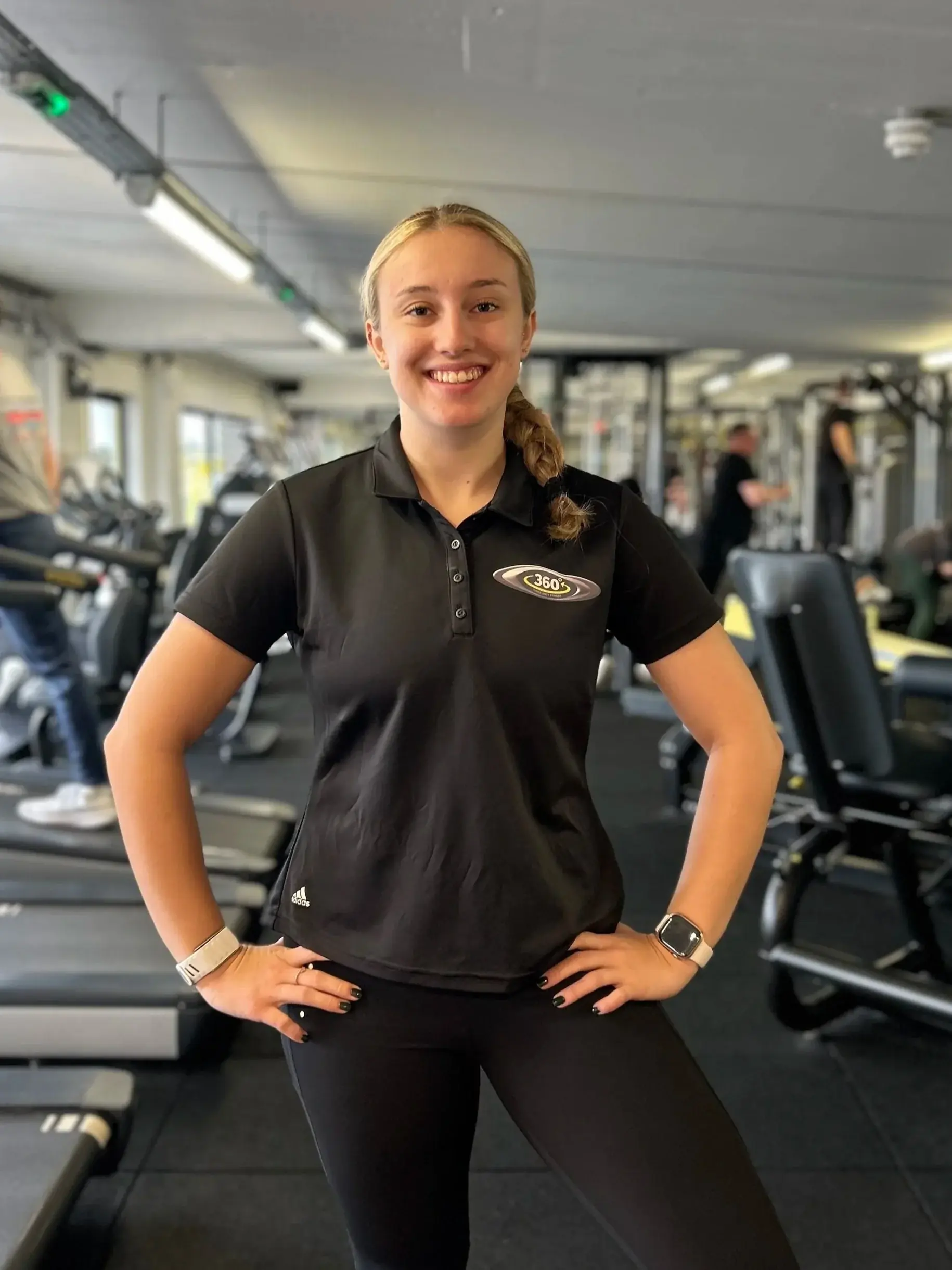 A personal trainer in a Three Sixty Fitness polo shirt on the gym floor