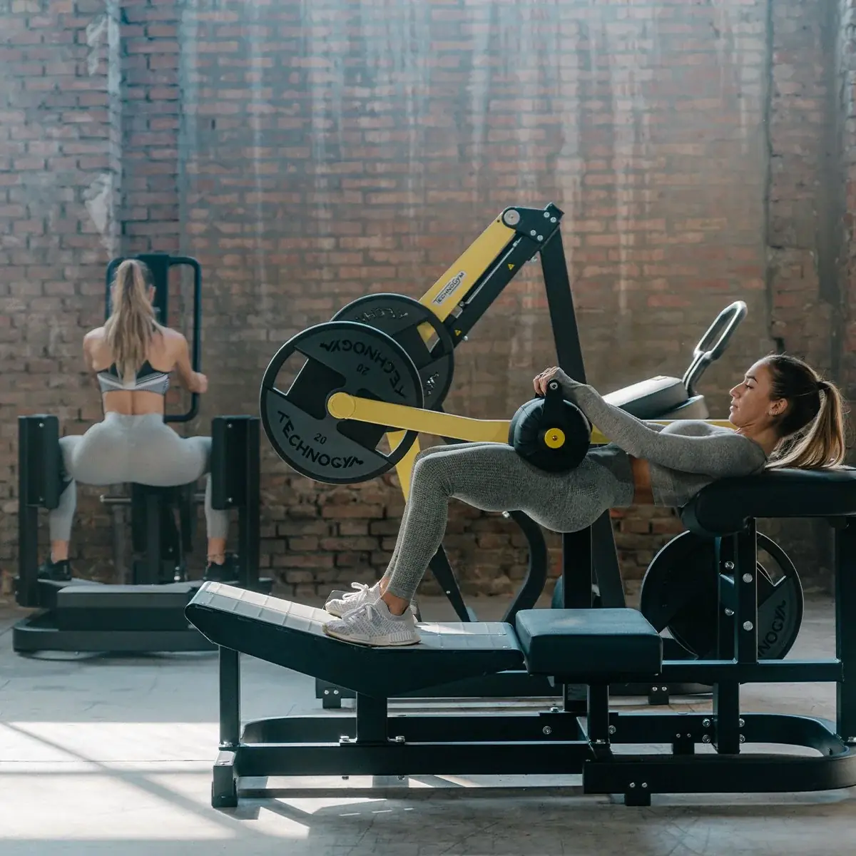 Two people using a Technogym Pure Strength leg press